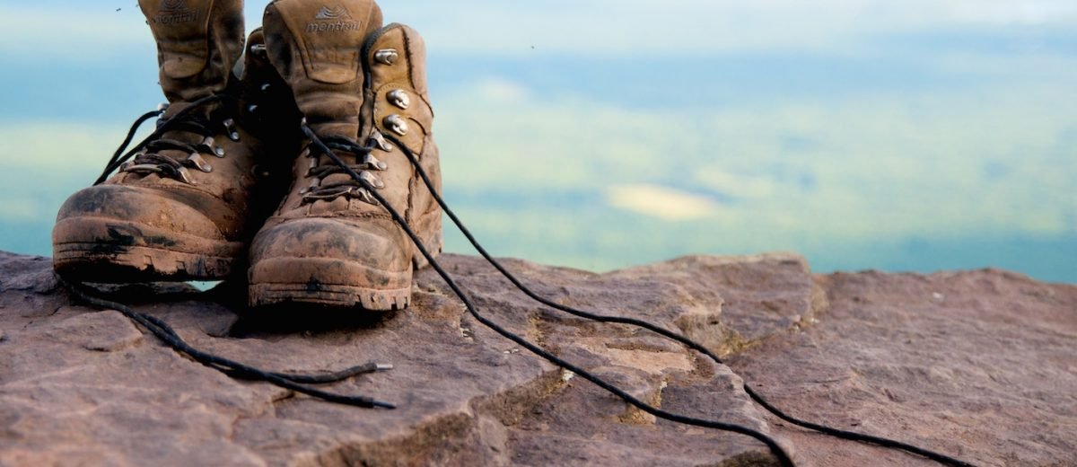 Worn hiking boots resting on rock above a mountain landscape